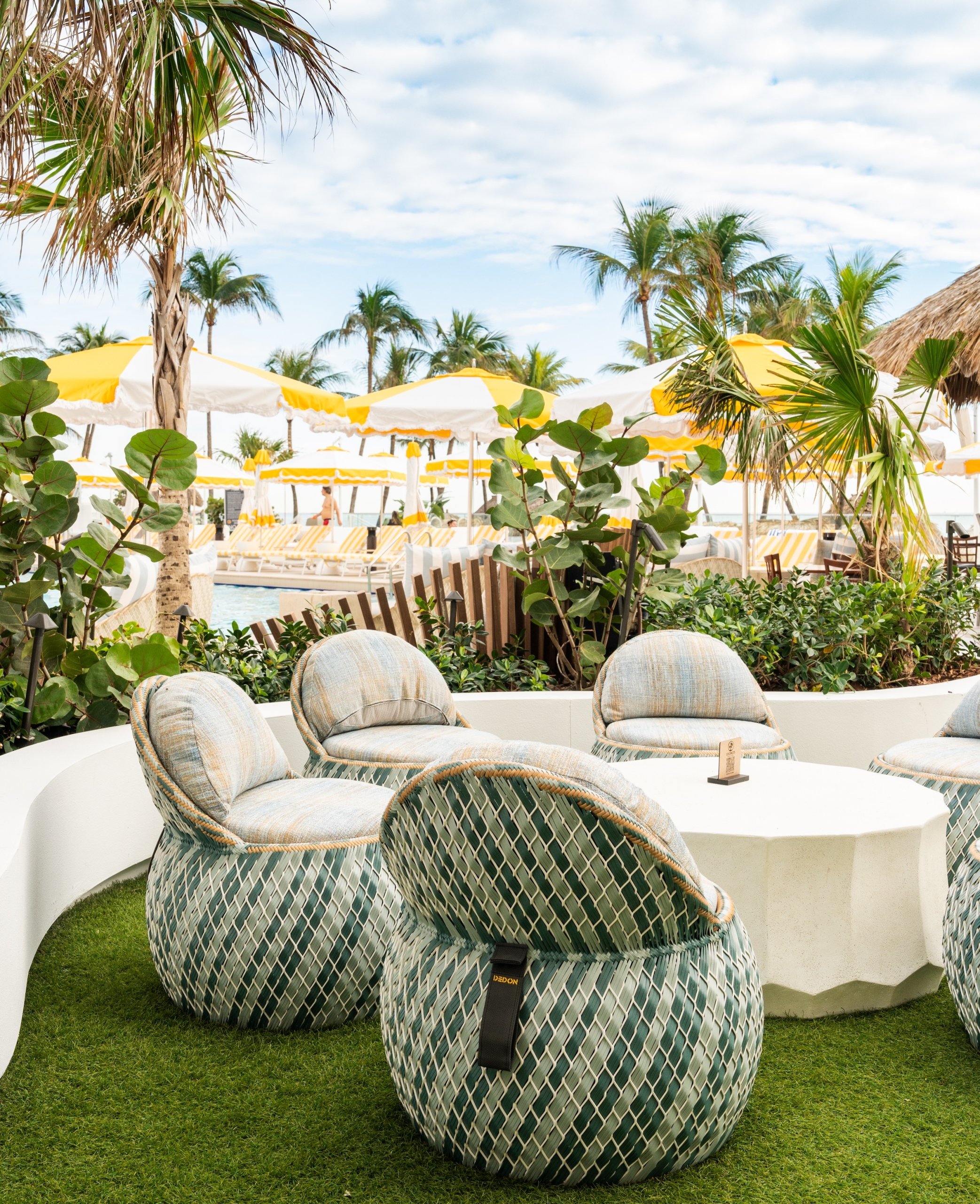 A white round table and unique green chairs surrounded by palm trees and green plants at Palm Court