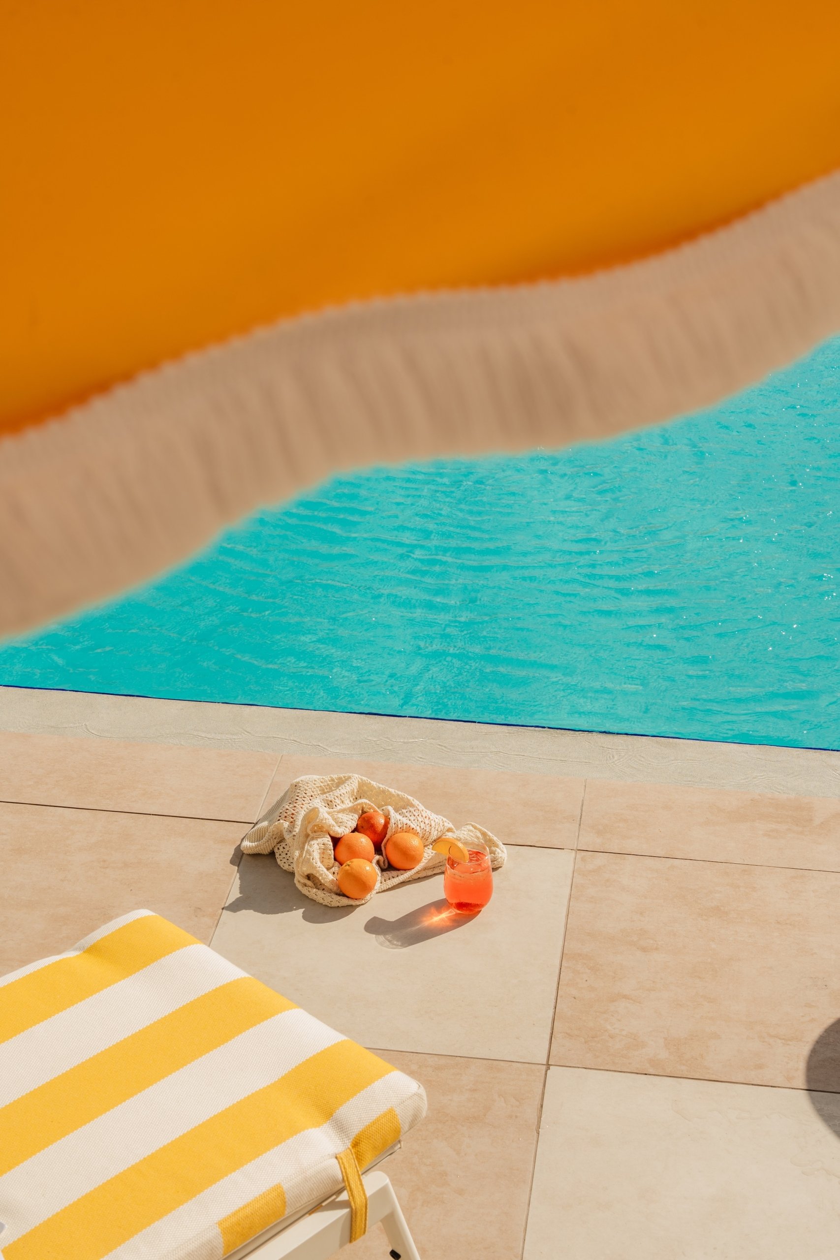 oranges and a cocktail near outdoor swimming pool