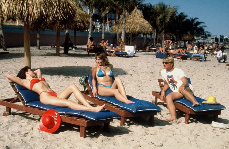Three people laying down beach chairs in Miami beach