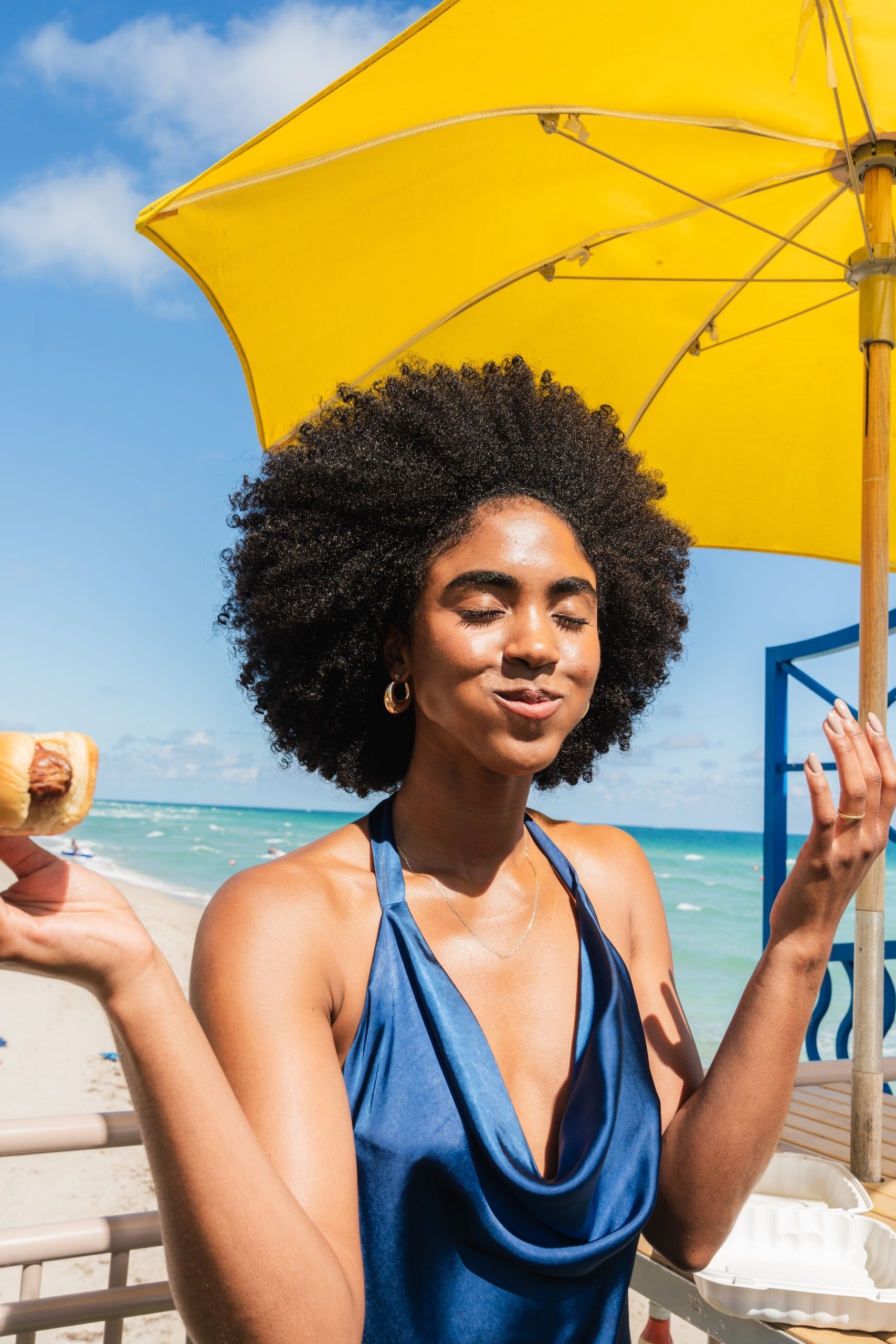 A woman under a yellow parasol from Sandbar at Newport PIer
