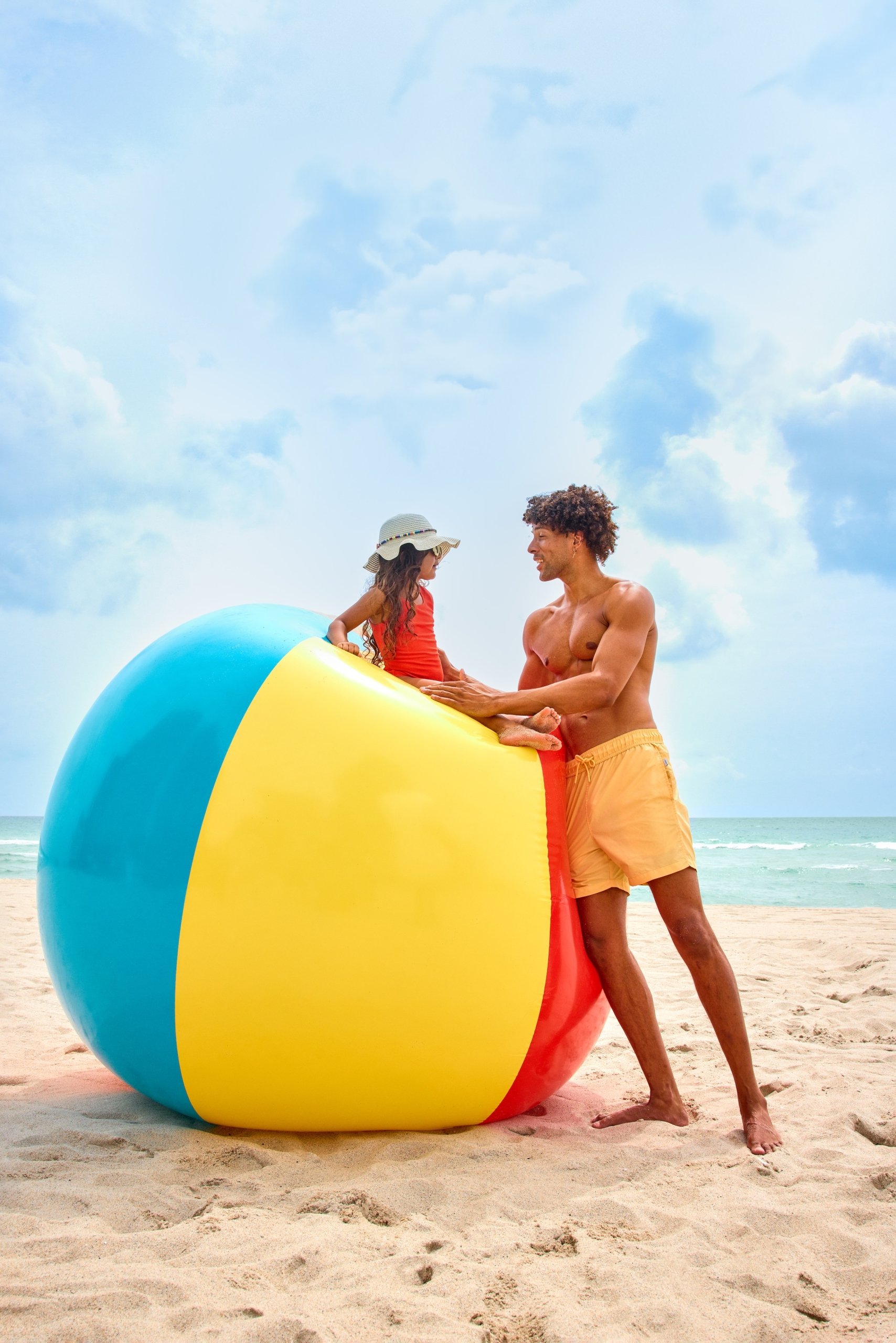 father and daughter play with large beach ball