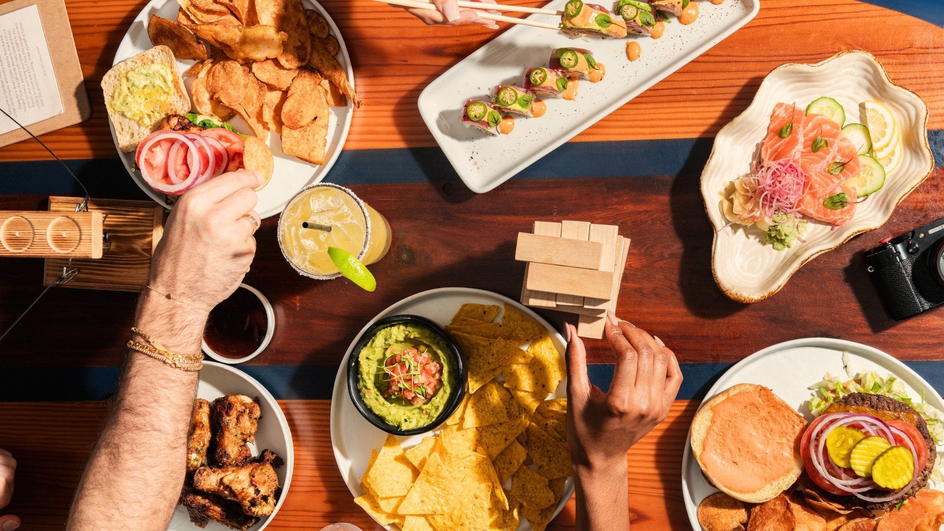 Various dishes on a wooden table from Sandbar at Newport Pier