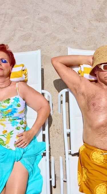 Elderly Couple in bright bathing suits sunbathing on the beach