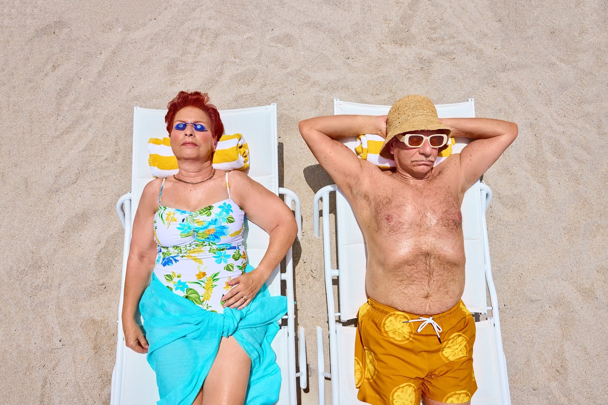 Elderly Couple in bright bathing suits sunbathing on the beach
